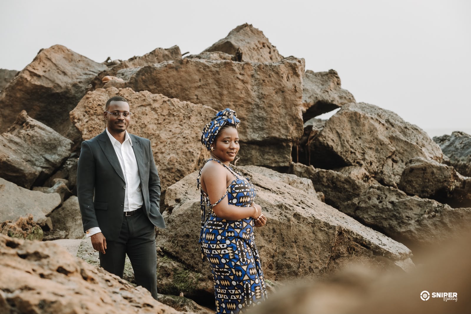 Josias e Merlene juntos sobre as rochas, mar ao fundo